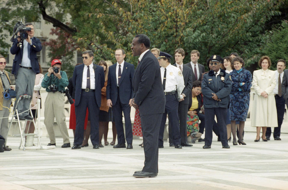 FILE - In this Nov. 1, 1991, file photo, newly sworn-in Supreme Court Justice Clarence Thomas talks to reporters while posing on the plaza of the court in Washington. Thomas is now the longest-serving member of a court that has recently gotten more conservative, putting him in a unique and potentially powerful position, and he’s said he isn’t going away anytime soon. With President Donald Trump’s nominees Neil Gorsuch and Brett Kavanaugh now on the court, conservatives are firmly in control as the justices take on divisive issues such as abortion, gun control and LGBT rights. (AP photo/Dennis Cook, File)