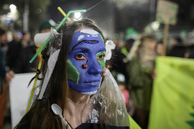 An activist with her face painted as a waste-ridden planet Earth attends a protest against widespread illegal logging and lack of policy response that has left two foresters dead earlier this year