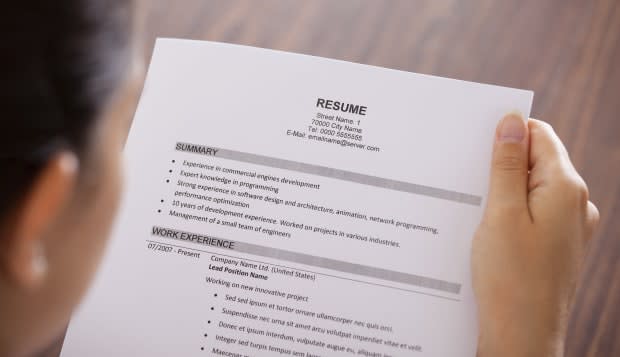 Close-up Of Young Businesswoman Reading Resume At Desk