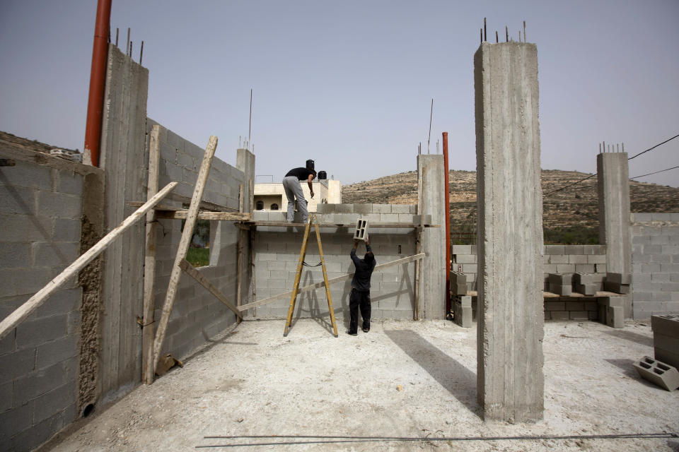 In this photo taken Monday, March 3, 2014, Palestinians work in a construction site in the West Bank village of Lubban al-Sharkiyeh. Ahmed Awais has been desperate to get out of his parents' cramped home where he, his wife and three pre-school children share one room, sleeping on mattresses on the floor at night. (AP Photo/Sebastian Scheiner)