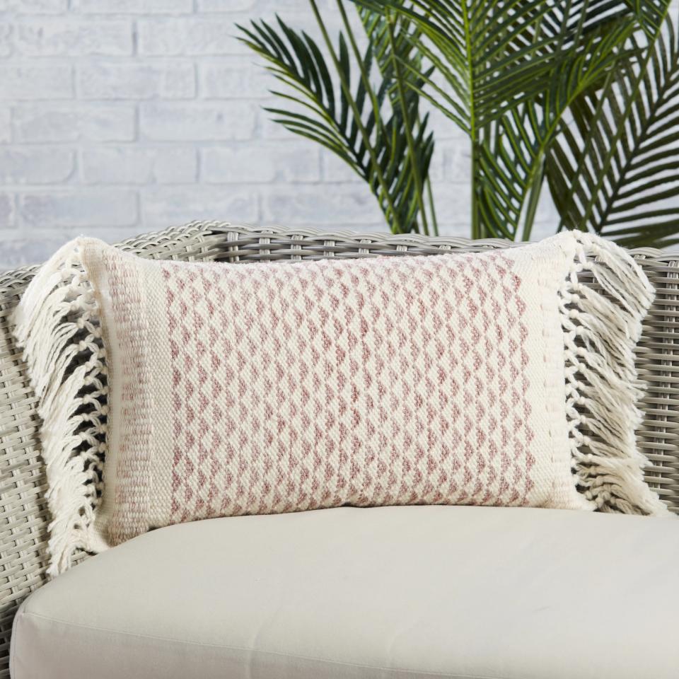 The rectangular shaped pillow with fringe on a chair
