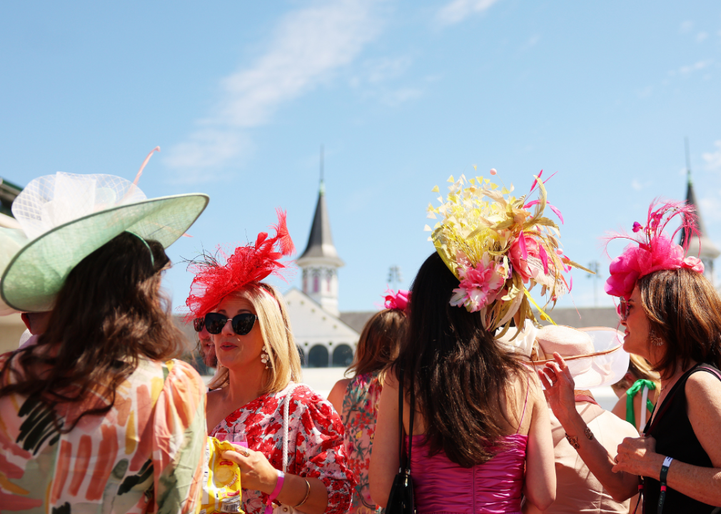 Spectators wearing festive hats look on in the paddock.