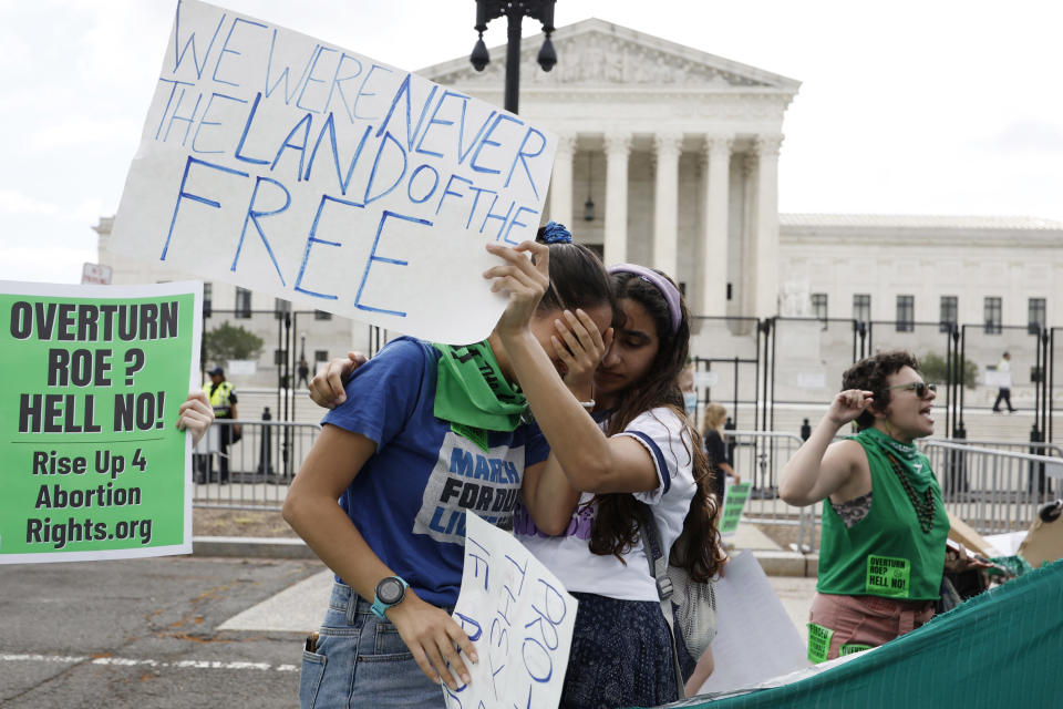 Protesters hold each other and cry in front of the Supreme Court building