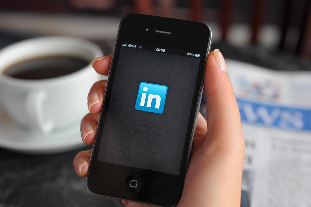 Astanbul, Turkey - December 14, 2011: Woman hand holding an touching an Apple iPhone 4 in a coffee shop. iPhone 4 displaying start up screen of LinkedIn application. The iPhone 4 is a touchscreen slate smartphone and the fourth generation iPhone, developed by Apple Inc.