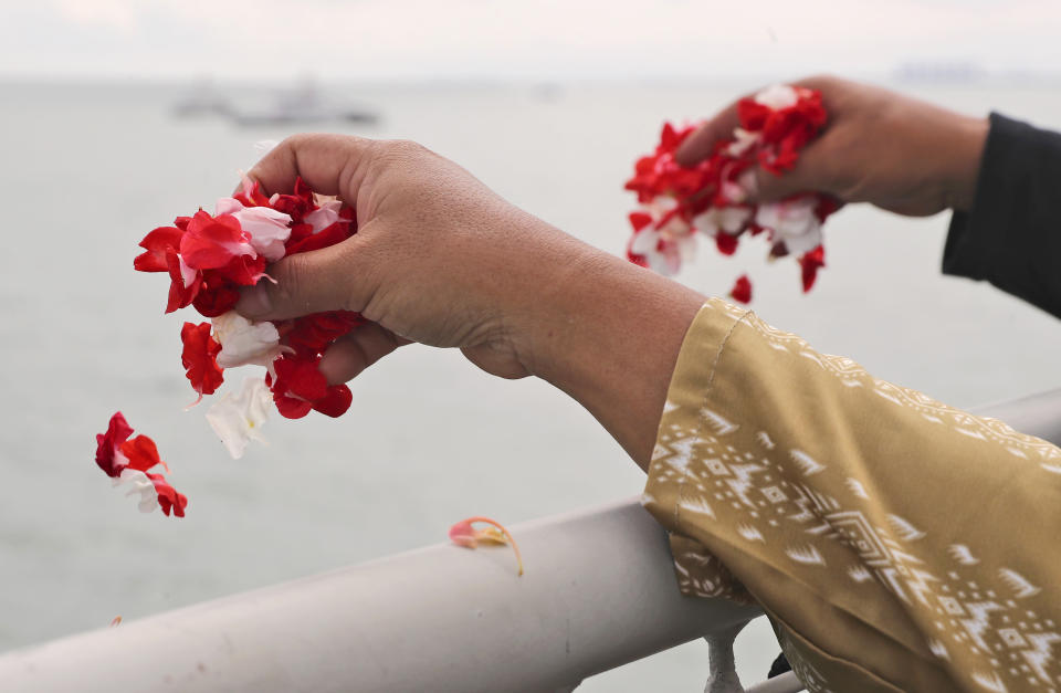 Relatives sprinkle flowers into the Java Sea where Sriwijaya Air flight SJ-182 crashed on Jan. 9 killing all of its passengers, during a memorial ceremony held on deck of Indonesian Navy Ship KRI Semarang, near Jakarta in Indonesia, Friday, Jan. 22, 2021. (AP Photo/Tatan Syuflana)