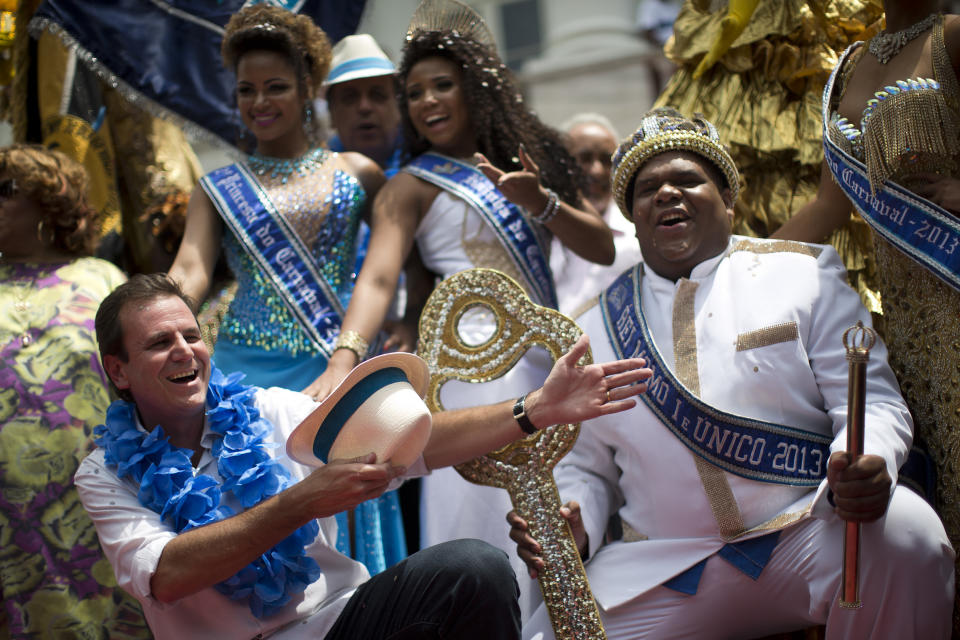 Rio de Janeiro's Mayor Eduardo Paes, left, gestures to the mythical jester figure who reigns over Carnival, this year's King Momo; the crowned and costumed Milton Rodrigues Junior, as he holds the key of the city at the official ceremony kicking off the five day bash, in Rio de Janeiro, Brazil, Friday, Feb. 8, 2013. (AP Photo/Felipe Dana)