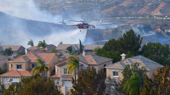 A helicopter drops water near homes in the Anaheim Hills neighborhood in Anaheim, California on October 9, 2017.