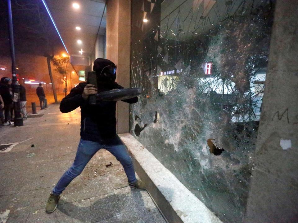 A protester smashes the window of a bank as demonstrations against the government continue in Beirut: Reuters