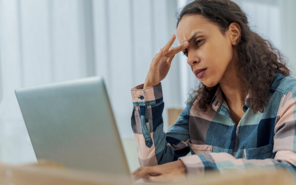 Worried business woman face looking at laptop in office. Tired overworked lady feeling eye strain after using computer working from home. Headache, visual fatigue and eyestrain concept.