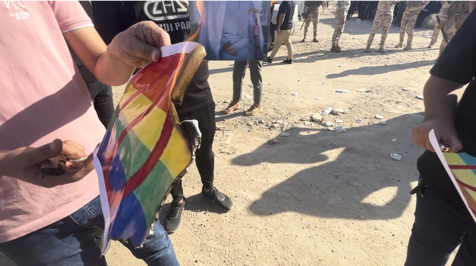 A protester burns a LGBTQ+ rainbow flag as hundreds of followers of the influential Iraqi Shiite cleric and political leader Muqtada Sadr stand outside the Swedish embassy in Baghdad, Iraq, Thursday, June 29, 2023, in protest of the burning of a Quran in Sweden. An Iraqi security official has said the Swedish embassy was evacuated by security forces after the protesters breached the building, raising pictures of Sadr and flags of his militia, the Mahdi Army. (AP Photo/Ali Jabar)