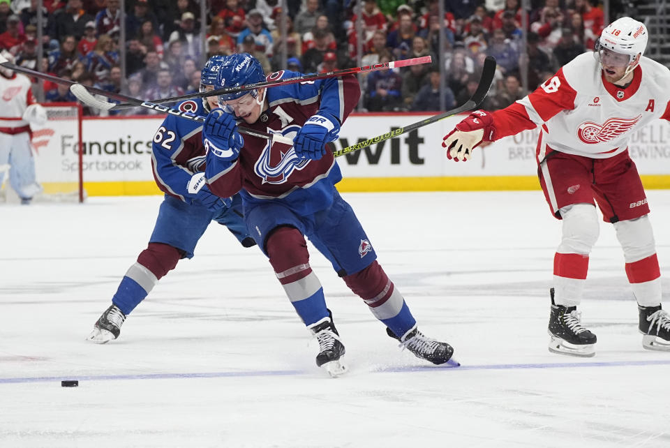 Colorado Avalanche defenseman Cale Makar, front left, struggles to collect the puck, while Detroit Red Wings center Andrew Copp loses his stick during the second period of an NHL hockey game Wednesday, March 6, 2024, in Denver. (AP Photo/David Zalubowski)