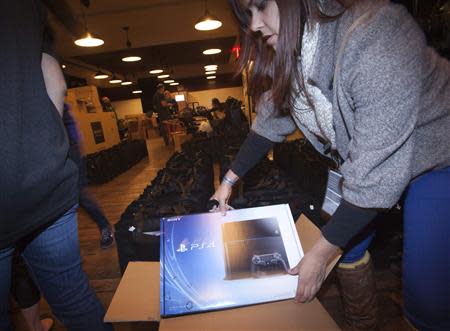 A Sony employee takes a Playstation 4 out of the box in advance of a special sale event put on by Sony at the Standard Hotel in New York November 14, 2013. REUTERS/Carlo Allegri