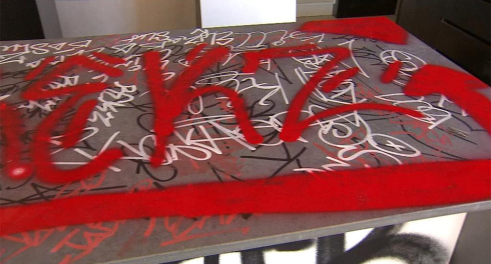 Red, white and black graffiti covering a new kitchen bench.