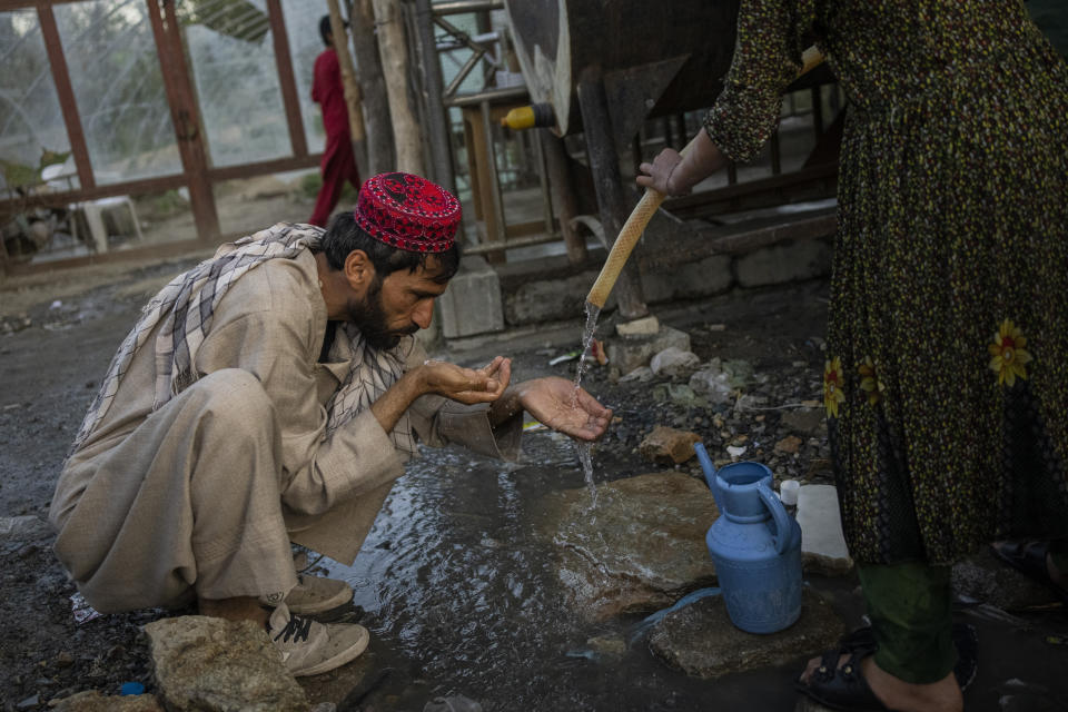 A displaced Afghan man drinks from a water tank at an internally displaced persons camp in Kabul, Afghanistan, Monday, Sept. 13, 2021. (AP Photo/Bernat Armangue)