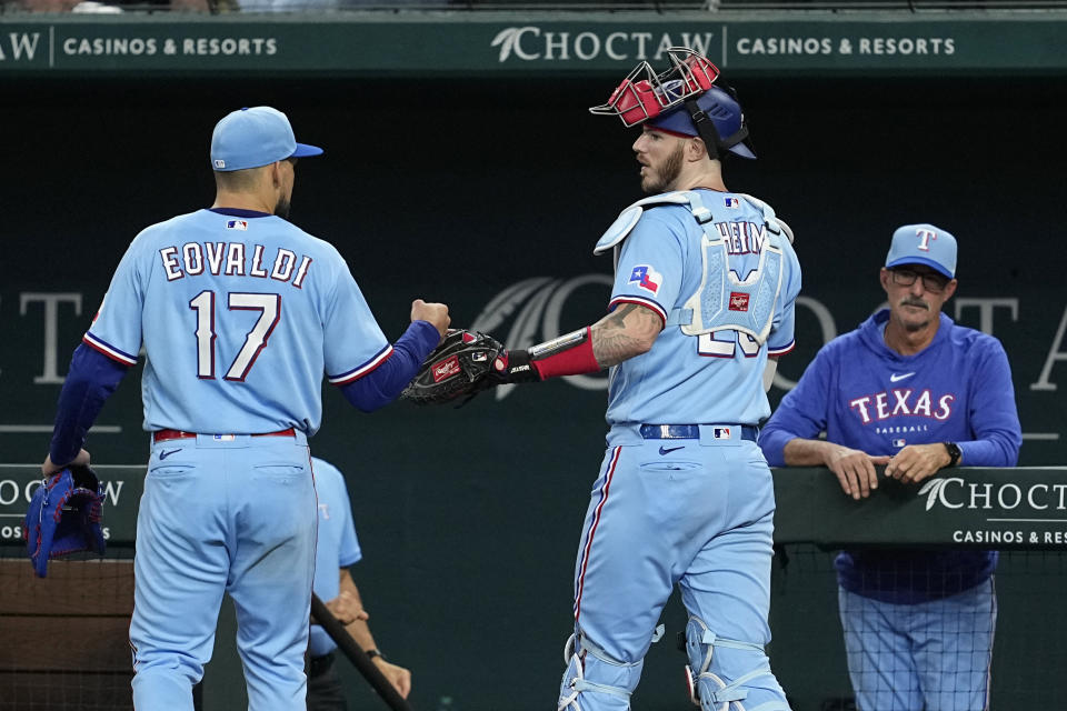 Texas Rangers' Nathan Eovaldi (17) and catcher Jonah Heim, center, talk as they walk past pitching coach Mike Maddux, right, into the dugout after working against the Seattle Mariners in the sixth inning of a baseball game, Sunday, June 4, 2023, in Arlington, Texas. (AP Photo/Tony Gutierrez)