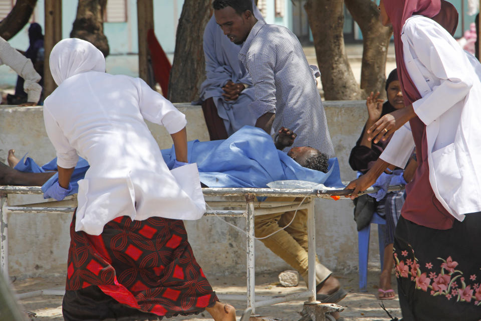 Medical workers help a man who was wounded in a car bomb attack, at Medina hospital, in Mogadishu, Somalia, Monday, July 22, 2019. A Somali police officer says a car bomb in the Somali capital has killed at least 10 people. Capt. Mohamed Hussein said at least 15 others were injured when the car bomb parked near a busy security checkpoint on the city's airport was detonated by remote control. (AP Photo/Farah Abdi Warsameh)