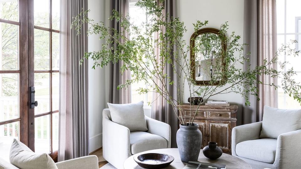 a living room with a chandelier and a table and plum brown curtains