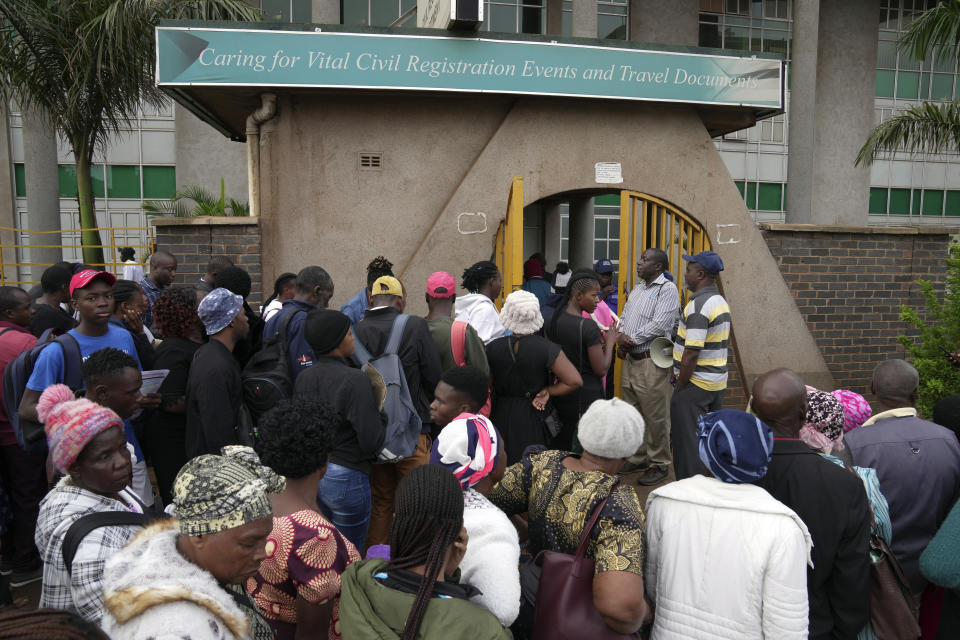 Travelers are seen in a queue outside the passport offices in Harare, Wednesday, Dec. 20, 2023. Atop many Christmas wish lists in economically troubled Zimbabwe is a travel document and people are flooding the passport office this holiday season ahead of a price hike planned in the New Year. The desperation at the office in the capital is palpable as some people fear the hike could push the cost of obtaining a passport out of reach and economic gloom feeds a surge in migration. (AP Photo/Tsvangirayi Mukwazhi)
