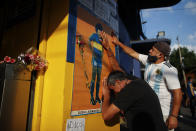 Hinchas acongojados frente a un afiche de Diego Maradona en la entrada de La Bombonera, el estadio del club Boca Juniors, en Buenos Aires, el miércoles 25 de noviembre de 2020. Tenía 60 años. (AP Foto/Natacha Pisarenko)