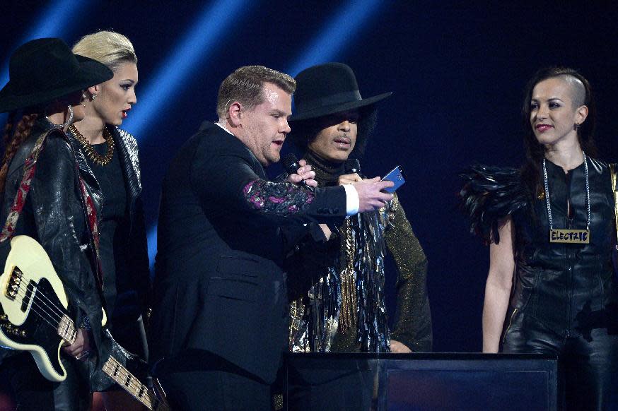 CAPTION ADDS THE NAMES OF THE GROUP 3RDEYEGIRL Host James Corden, centre, takes a picture onstage with US recording artist Prince and group 3rdeyegirl Donna Grantis, Hannah Ford and Ida Nielsen, during at the BRIT Awards 2014 at the O2 Arena in London on Wednesday, Feb. 19, 2014. (Photo by Jon Furniss/Invision/AP)