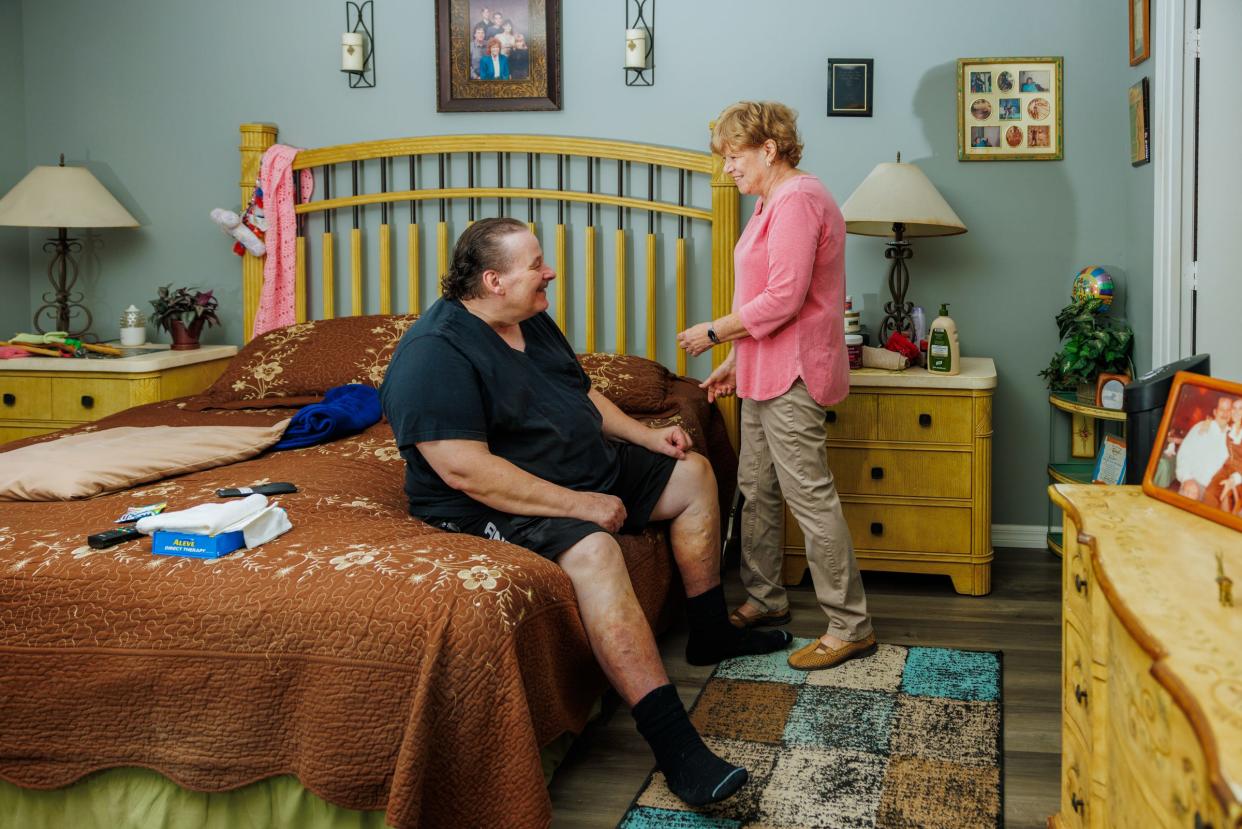 Wendy Jones smiles at her husband while he sits on the bed