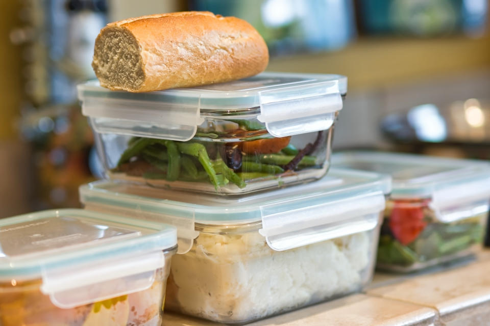 Containers of leftover food are pictured stacked on a kitchen counter.