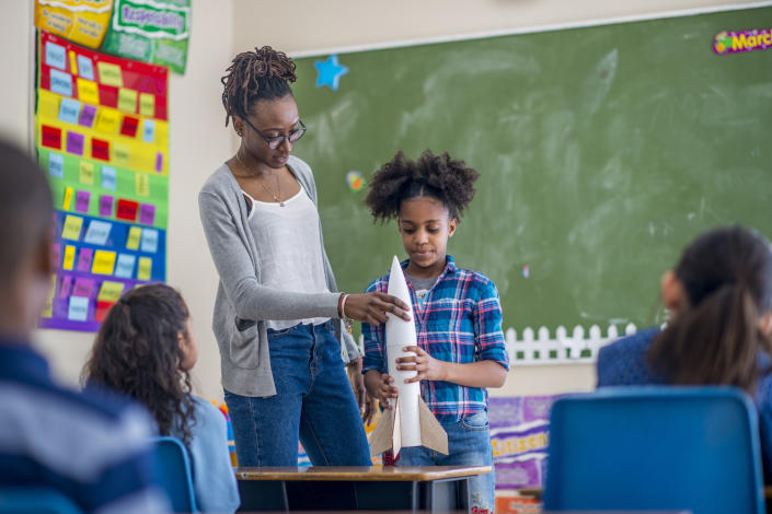 A teacher showing a student a model rocket