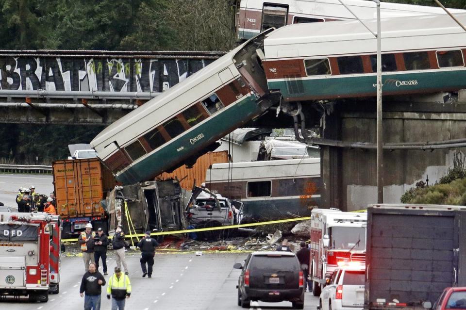 <span class="icon icon--xs icon__camera">  </span> <span class="credit font--s-m upper black"> <b>Elaine Thompson</b> </span> <div class="caption space-half--right font--s-m gray--med db"> Cars from an Amtrak train lay spilled onto Interstate 5 below alongside smashed vehicles as some train cars remain on the tracks above Monday, Dec. 18, 2017, in DuPont, Wash. </div>