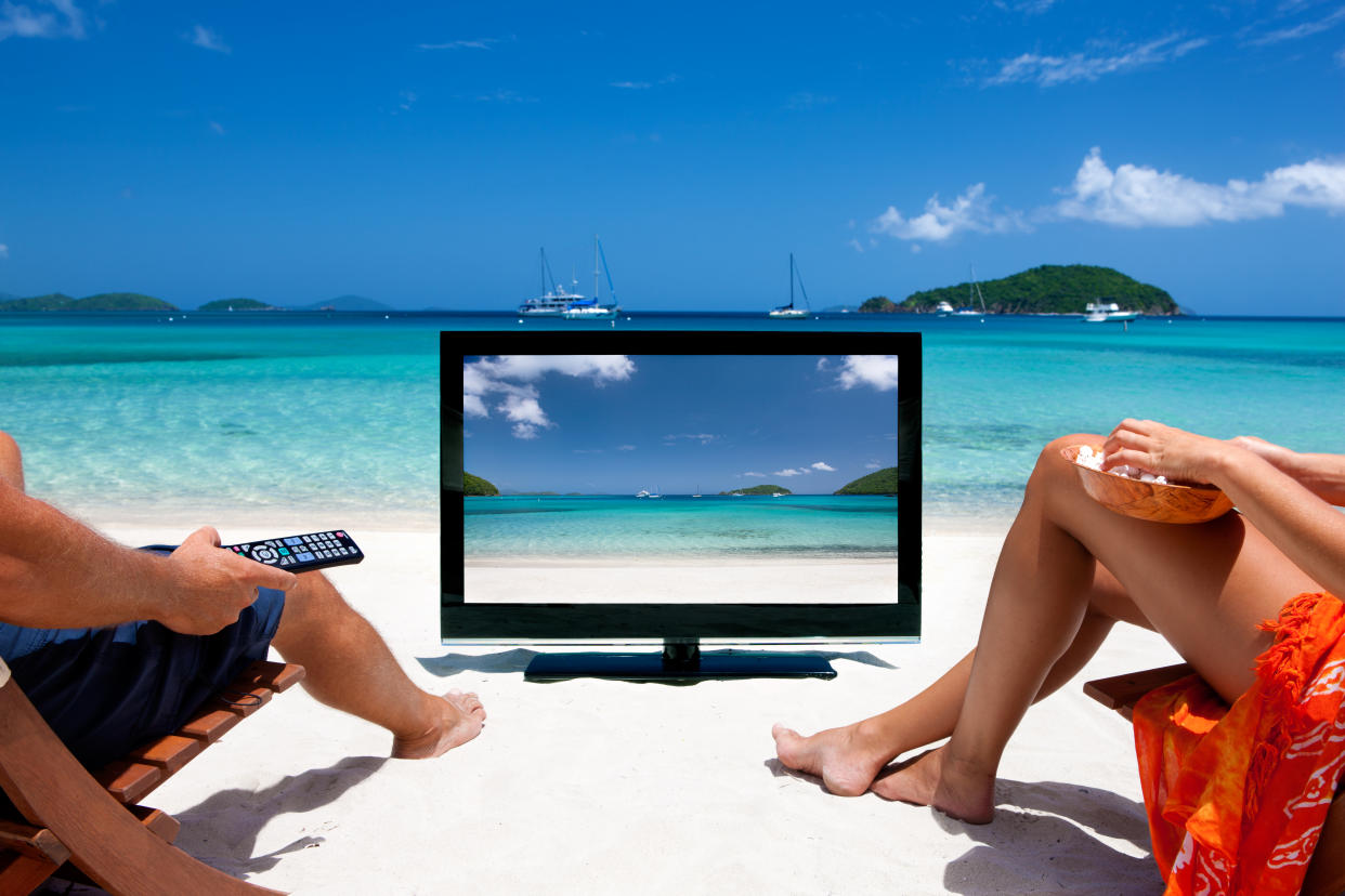 unrecognizable couple watching television at a tropical Caribbean beachview images from the same series: