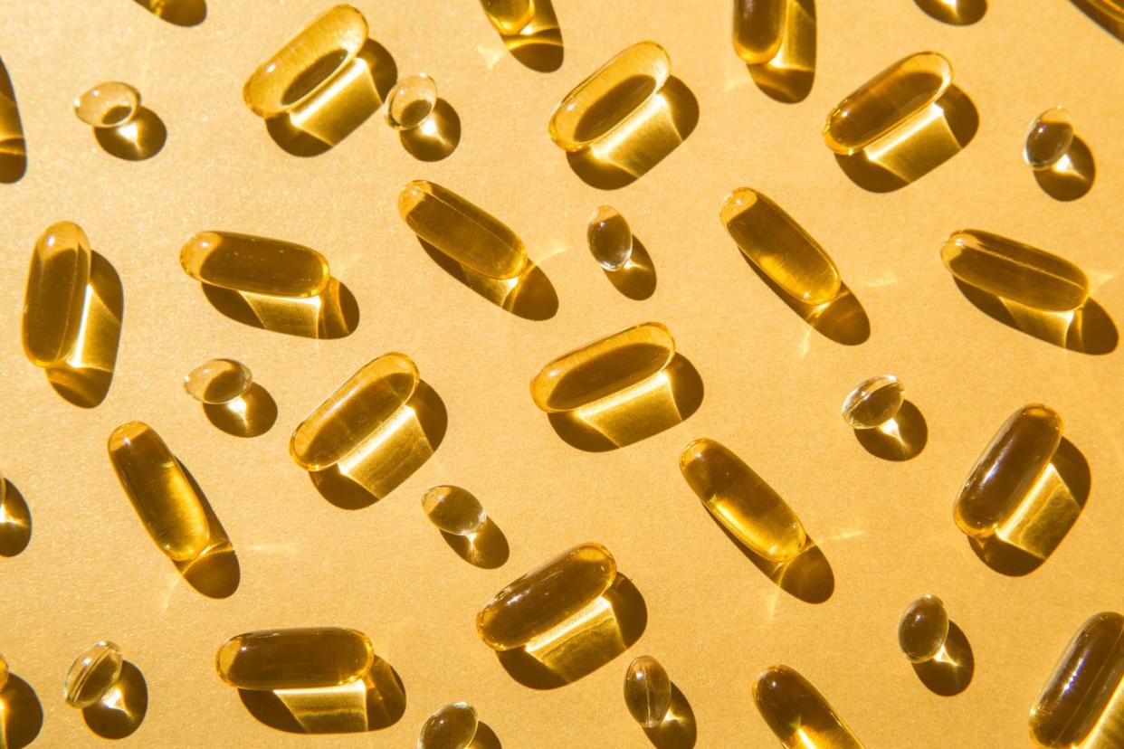 soft capsules of fish oil with omega 3 and vitamin d on a golden background