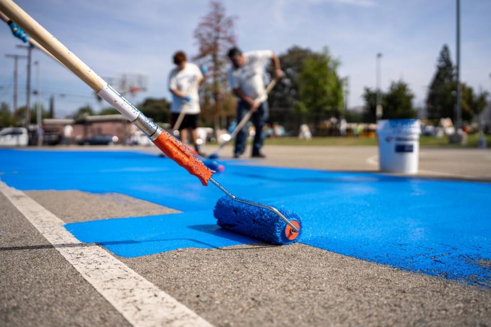 Light- and heat-reflecting paint is rolled onto a basketball court in Los Angeles (Courtesy of GAF)