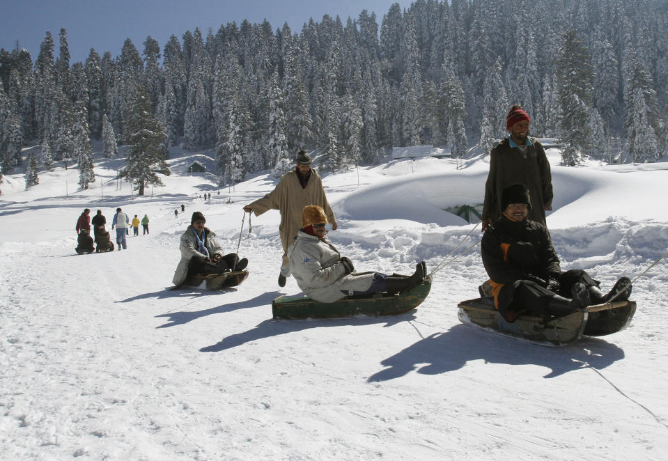 FILE- In this Feb. 7, 2013 file photo, Kashmiri laborers pull tourists on sleds in Gulmarg, some 55 kilometers (34 miles) from Srinagar, India. Kashmir’s pristine Alpine landscape, ski resorts, lake houseboat stays and uninterrupted acres of apple orchards have long made it a global tourist draw. (AP Photo/Mukhtar Khan, File)