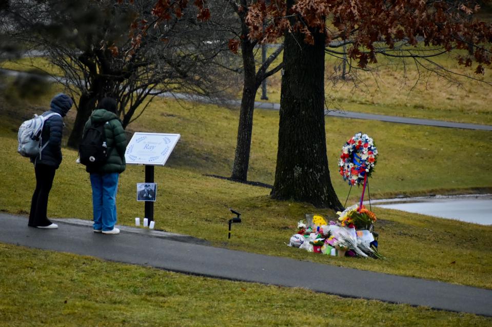 A pair of students observe a memorial set up for Ray Rattray near the Gunk at SUNY New Paltz.