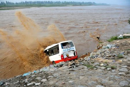An abandoned bus filled with sand bags is used to build a makeshift dike at a flooded area in Xingtai, Hebei Province, China, July 21, 2016. REUTERS/Stringer