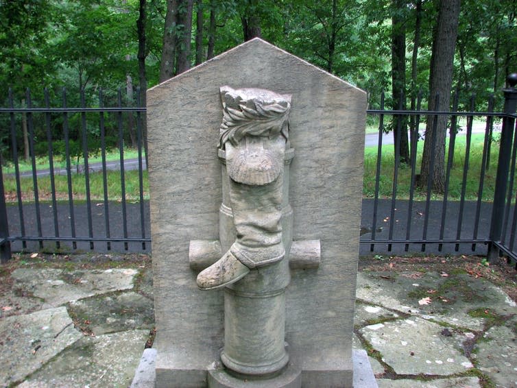 Statue of a boot hanging on a post in a park,