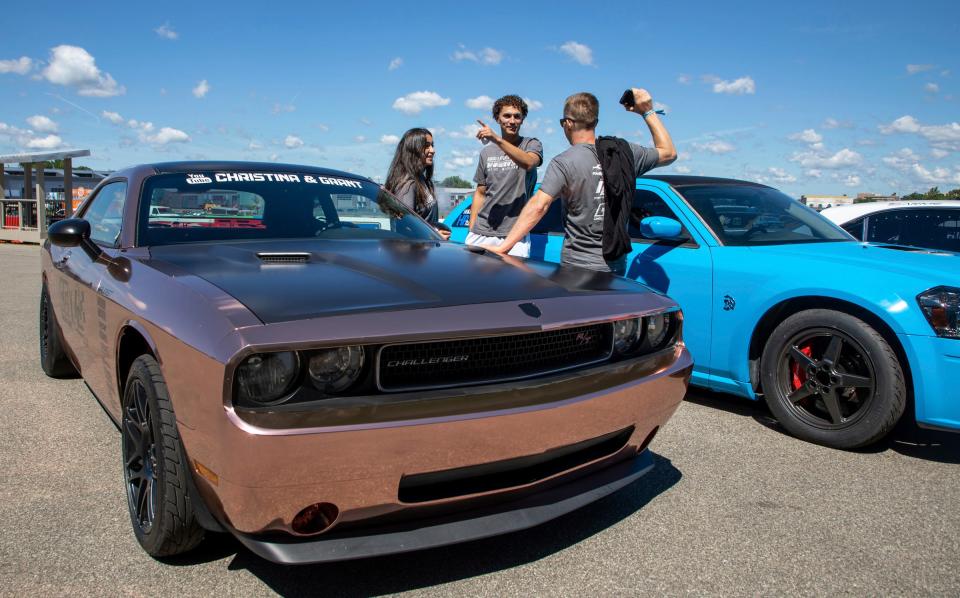 Christina Roki, 21, left, stands next to her partner Grant Sloan, 21, and their Dodge vehicle during the Roadkill Nights 2022 preview event at the M1 Concourse in Pontiac on Aug. 12, 2022.