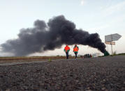 <p>Two union activists in fluorescent vests walk toward the Normandie Bridge outside of Le Havre, western France, during a blockade action, May 26, 2016. The cloud of black smoke is from burning tires. French Prime Minister Manuel Valls says he is open to "improvements and modifications" in a labor bill that has sparked intensifying strikes and protests, but will not abandon it. (Raphael Satter/AP) </p>