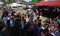 Migrants stand in line for breakfast at a temporary shelter in Tecun Uman, Guatemala in the border with Mexico, Sunday, Jan. 19, 2020. Mexican authorities have closed a border entry point in southern Mexico after thousands of Central American migrants tried to push across a bridge between Mexico and Guatemala. (AP Photo/Moises Castillo)