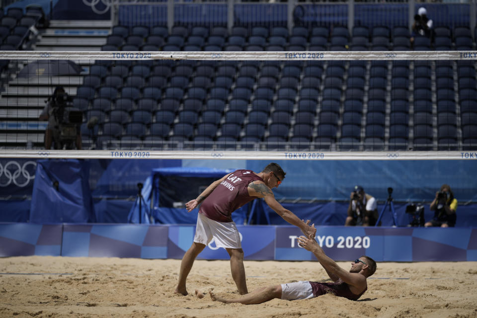 Martins Plavins, center, of Latvia, celebrates with teammate Edgars Tocs, after winning a men's beach volleyball quarterfinal match against Brazil at the 2020 Summer Olympics, Wednesday, Aug. 4, 2021, in Tokyo, Japan. (AP Photo/Felipe Dana)