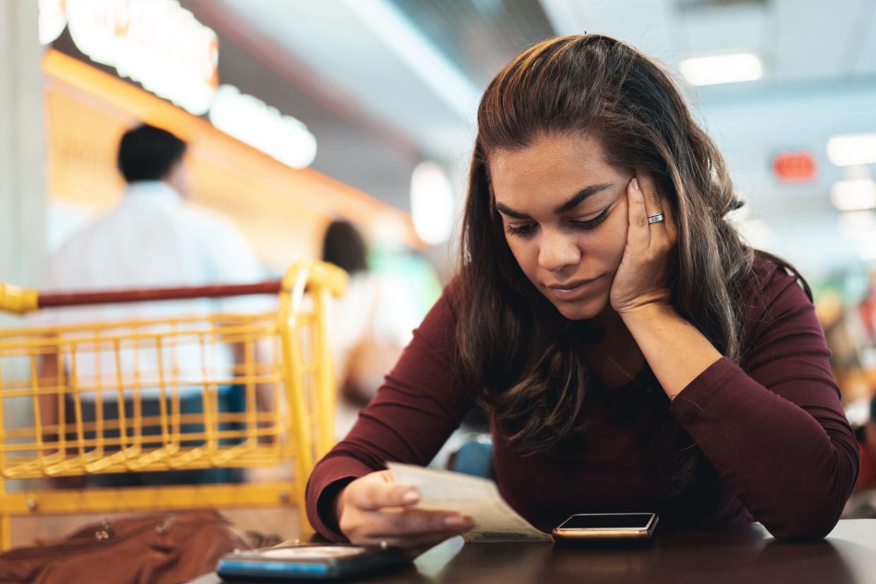 woman looking over receipt while sitting in table at supermarket