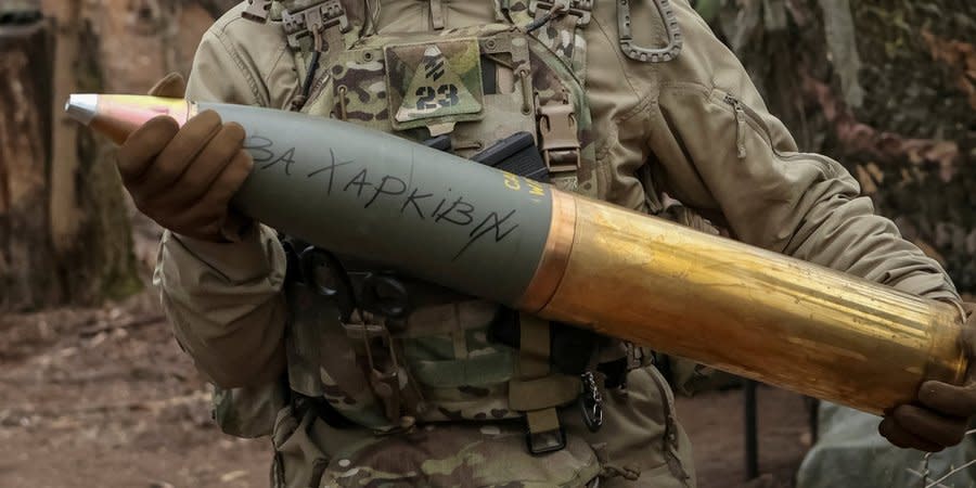 A Ukrainian soldier holds an artillery shell with the inscription 