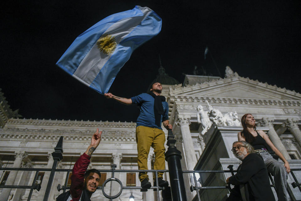 Demonstrators climb to the fence of Congress during protests against economic measures announced by President Javier Milei in Buenos Aires, Argentina, Wednesday, Dec. 20, 2023. Milei announced initiatives to transform the country's struggling economy, including easing government regulation and allowing privatization of state-run industries as a way to boost exports and investment. (AP Photo/Gustavo Garello)