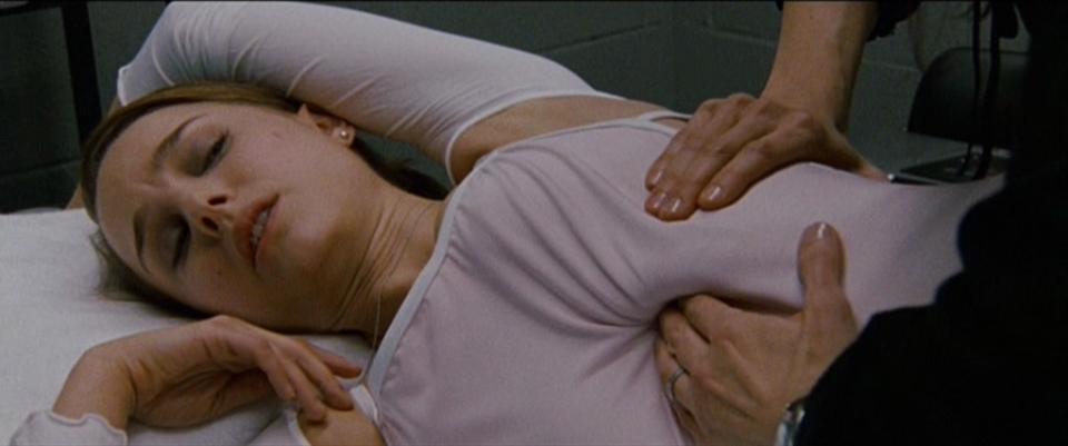 Portman lying on her side as she's given physical therapy for her ribs