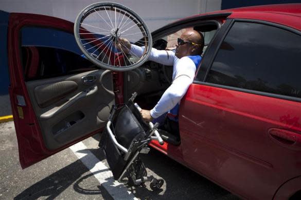 Jesus Aguilar, 48, a member of Venezuela's Paralympics team puts his wheelchair into his car after a training session in Barquisimeto April 27, 2012.