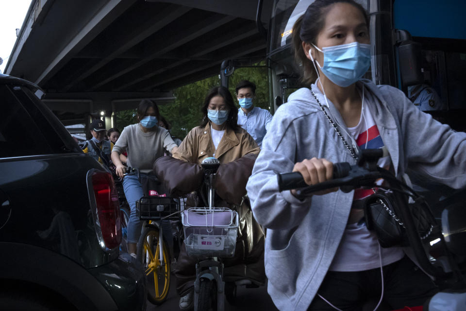 People wearing face masks to protect against COVID-19 make their way through traffic at an intersection in the central business district in Beijing, Thursday, Sept. 16, 2021. China on Thursday reported several dozen additional locally-transmitted cases of coronavirus as it works to contain an outbreak in the eastern province of Fujian. (AP Photo/Mark Schiefelbein)