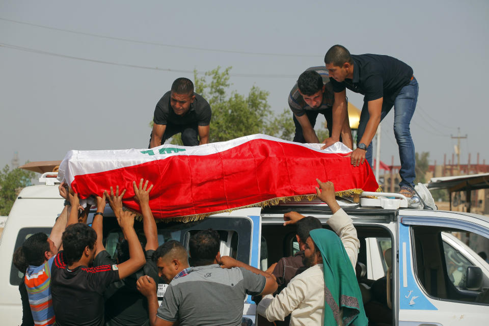 Family members of Ali Jamal, 23, who was killed in a bomb attack, load his flag-draped coffin onto a vehicle before burial in the Shiite holy city of Najaf, 100 miles (160 kilometers) south of Baghdad, Iraq, Monday, May 12, 2014. Bombings and shootings killed several people in areas south of the Iraqi capital on Monday, authorities said. (AP Photo/Jaber al-Helo)