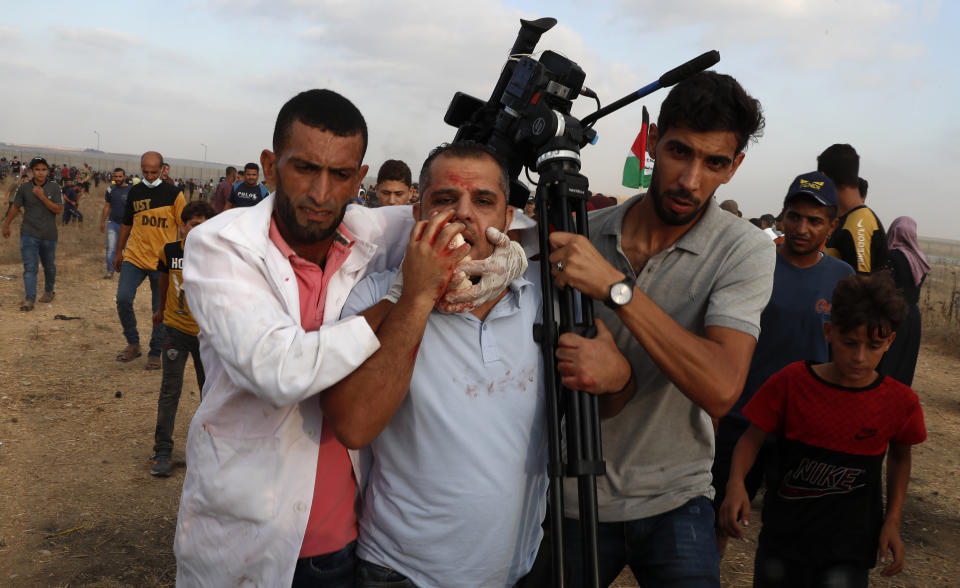 Medics and protestors evacuate a wounded of cameraman of Asem Shehada, from the fence of Gaza Strip border with Israel, during a protest marking the anniversary of a 1969 arson attack at Jerusalem's Al-Aqsa mosque by an Australian tourist later found to be mentally ill, east of Gaza City, Saturday, Aug. 21, 2021. (AP Photo/Adel Hana)