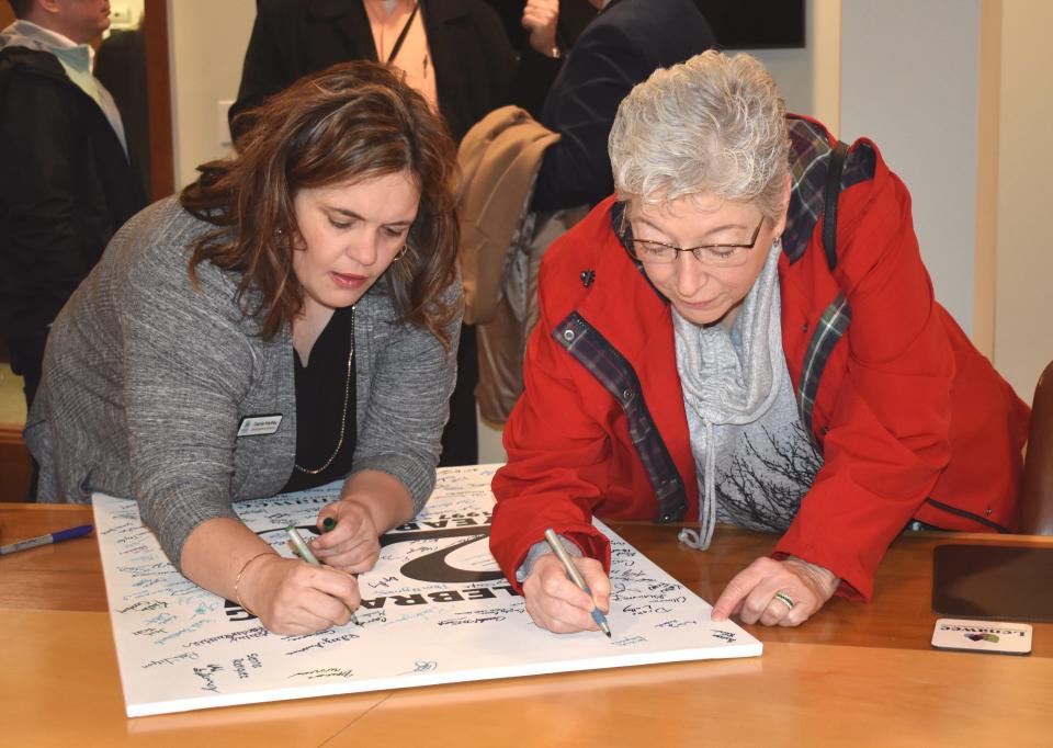 Carrie Hartley, left, development director at Habitat for Humanity of Lenawee County, and Linda Desjarlais, right, sign their names to a poster board commemorating the 25h anniversary of the Lenawee Community Foundation, Jan. 17, 2023, during a reception for the foundation's new president and CEO, Bronna Kahle. The community foundation turned 25 in 2022.