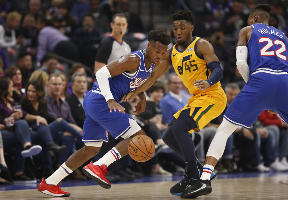 Sacramento Kings guard Buddy Hield, left, uses a screens by Richaun Holmes, right, as he tries to leave Utah Jazz guard Donovan Mitchell behind during the first quarter of an NBA basketball game in Sacramento, Calif., Friday, Nov. 1, 2019. (AP Photo/Rich Pedroncelli)