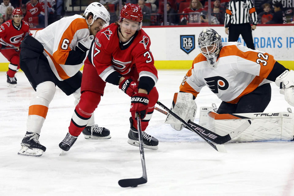 FILE - Carolina Hurricanes' Andrei Svechnikov (37) controls the puck between Philadelphia Flyers' Travis Sanheim (6) and goaltender Felix Sandstrom (32) during the second period of an NHL hockey game in Raleigh, N.C., Thursday, March 9, 2023. Svechnikov can only watch as his team begins a fifth straight trip to the NHL playoffs, as he faces months of recovery from knee surgery following an injury in March. (AP Photo/Karl B DeBlaker, File)